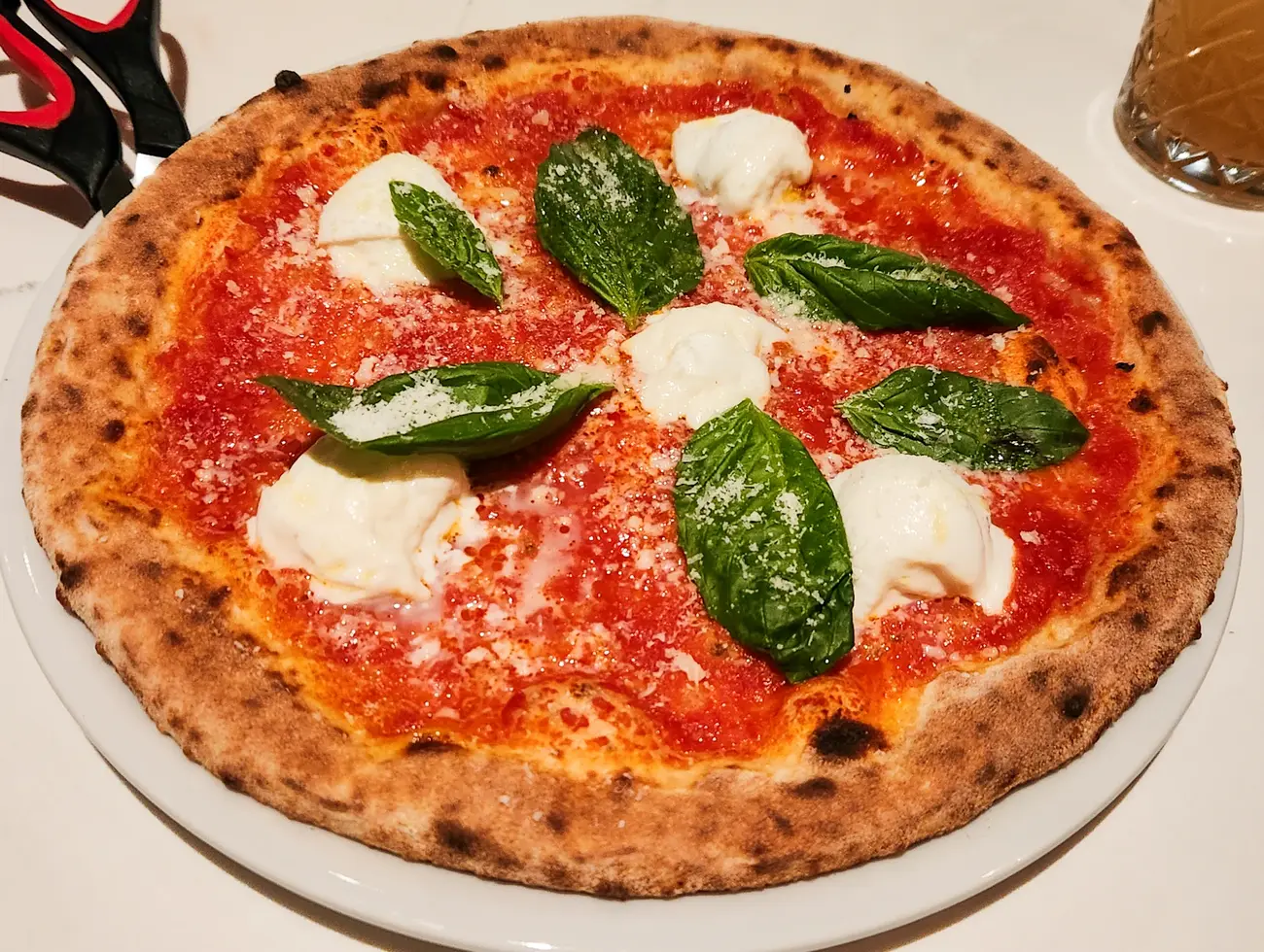 Pizza napolitaine à la tomate, burrata fondante et feuilles de basilic