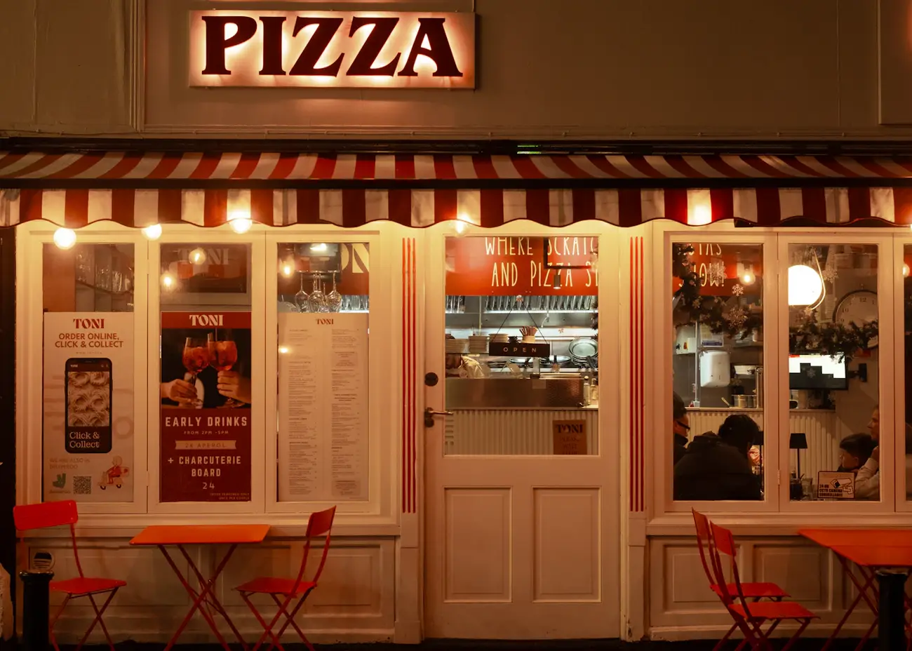 La devanture éclairée de la pizzeria le soir