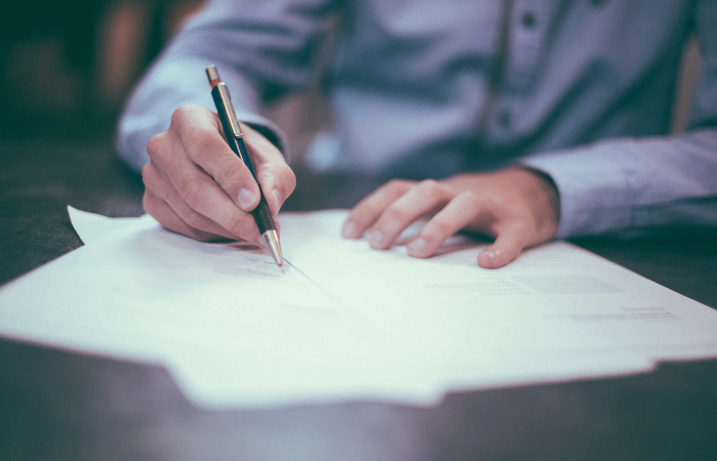Une main signe un document à un bureau